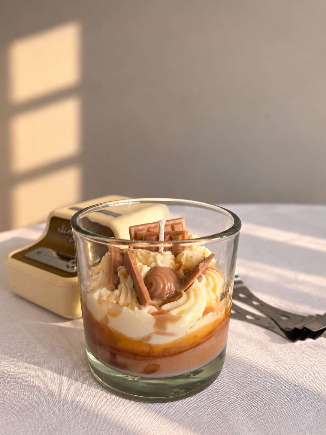 Vela de postre con crema, caramelo y chocolatitos en un vaso de vidrio